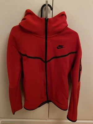 Nike tech zip hoodie röd - Säljer en röd Nike Tech zip hoodie i bra skick. Bekväm och varm hoodie i Tech Fleece-material med hel dragkedja, huva och fickor. Stilren och passar perfekt till vardags. 
