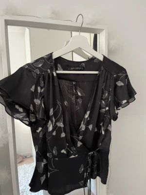 Omlott blus  - Så snygg omlott topp från Zara, svart med vitt mönster på. Man knyter den själv. Super snygg!! Säljer endast pga av fel storlek❤️