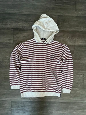 Randig hoodie  - Riktigt snygg hoodie med röda ränder över. Ingen aning vad det är för märke. Storleks lappen är bort klippt men är nästan helt säker att det är M. Vid fler funderingar kring plagget är det bara att skriva mvh FABIANFASHION