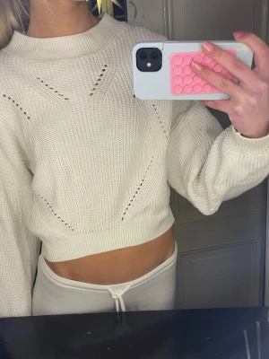 Vit croppad stickad tröja - Säljer en vit croppad stickad tröja med snygga hålmönster och ribbad kant vid hals och midja. Så himla fin! Som ny! Storlek 158/164 men passar som xs! 💘