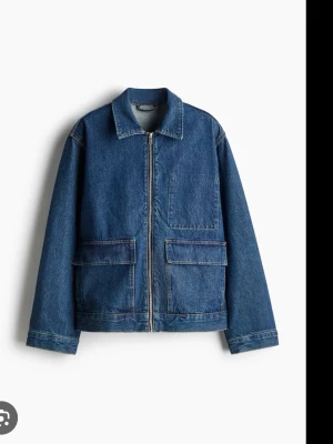 Blå jeansjacka med dragkedja från h&m - Säljer en klassisk blå jeansjacka från h&m med rak passform och stora fickor framtill. Jackan har dragkedja, krage och långa ärmar. Perfekt för dig som gillar enkel och stilren denim med lite streetkänsla.