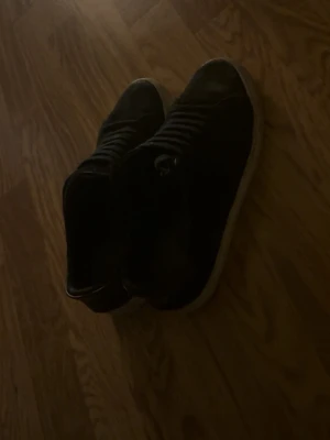 Svarta arigato skor storlek 42 - Svarta  arigato skor med snörning och vit platt sula. Skorna är tillverkade i skinn och har en klassisk rund tå. Passar dig som gillar stilrena och enkla skor med låg profil. Storlek EU 42, UK 8, US 9.
