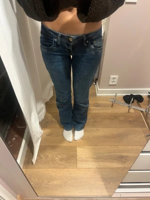 Blå bootcut jeans från LTB - Snygga blå jeans från LTB med klassisk femficksdesign och coola kontrastsömmar på bakfickan. Modellen har låg midja och bootcut-ben som ger en schysst siluett. Jeansen är tillverkade i jeansmaterial med dragkedja och knapp framtill.