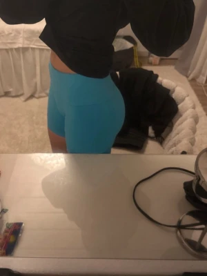 Blå tighta träningsshorts - Säljer ett par blå, tighta träningsshorts med hög midja. De är gjorda i ett stretchigt syntetmaterial som sitter skönt och följer kroppen. Perfekta för gymmet eller andra sportaktiviteter. Snygg och enkel design utan synliga detaljer.