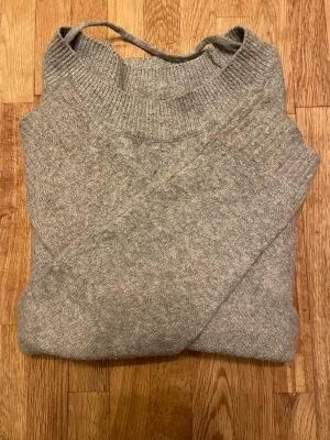 Grå stickad tröja från Vero Moda - Mysig grå stickad tröja från Vero Moda i storlek XS. Tröjan har rund hals med bred ribbad kant och långa ärmar. Perfekt för kyliga dagar och enkel att matcha med jeans eller kjol. Materialet är mjukt som inte sticks och ger en skön känsla hela dagen. I princip oanvänd. 