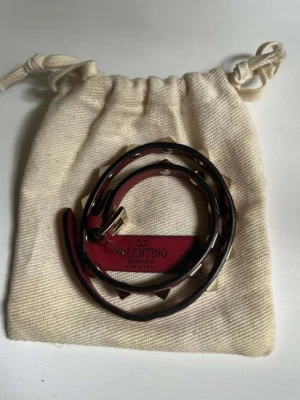 Röd Valentino skinnarmband med nitar - Säljer ett snyggt rött armband från Valentino Garavani.