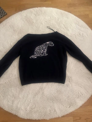 Mörkblå stickad offshoulder tröja från Subdued - Mysig mörkblå stickad tröja från Subdued med en stor leoparddetalj framtill. Är onesize men passar jättebra på en person som har XS-S. Tröjan är i bra skick, bara används två gånger. Dock tvättade en gång så lite kortare än på bilden, men annars är den som ny. 