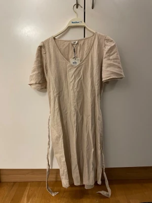 Beige linnéklänning från JDY - Säljer en beige, enkel och stilren klänning från JDY i stl XS. Tillverkad i linne, vilket gör den luftig och skön. Perfekt för varma dagar och en avslappnad look. Helt ny & oanvänd säljer för den var för stor:(