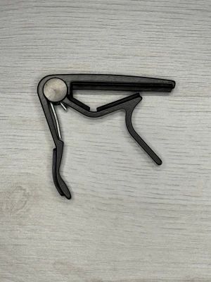 Jim Dunlop USA Capo – Professionell kapodaster - Hejsan!  En klassisk Jim Dunlop USA kapodaster till salu. Det är en mycket pålitlig och robust modell som sitter perfekt på greppbrädan utan att stämma ur gitarren.  Den är tillverkad i högkvalitativt material och är i mycket bra skick. Fungerar precis som den ska och har många år kvar att ge.  Specifikationer:  • Märke: Jim Dunlop (Made in USA)  • Typ: Kapodaster för gitarr  • Färg: Svart  • Skick: Mycket bra begagnat skick  Butikspris: 330 kr  Mitt pris: 149 kr  Säg till om du undrar något :)