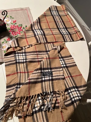 Biege scarf från burberry - Klassisk biege scarf från burberry. Gjord på 100% lammull 
