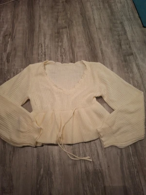 Vit stickad tröja med v-ringning - Supersöt vit stickad tröja från shein med v-ringad hals och volangkant. Tröjan har långa ärmar och en knytning i midjan. Aldrig andvänd då den upplevs kort på mig (174 cm), tröjan slutar lite över midjan på mig. Köpt för 250 kr priset kan förhandlas!