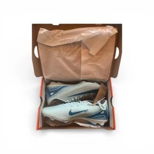 Nike Mercurial fotbollsskor ljusblå - Nike Mercurial fotbollsskor i ljusblå och blå färg med snörning och rund tå. Skorna har en platt sula med dobbar för gräsplan och är tillverkade i syntetmaterial. Snyggt randigt mönster på sidorna och klassisk Nike-logga. Perfekta för dig som vill ha grym touch på planen. Skorna är herrmodell i storlek 44,5 helt oanvända! Nypris är 799 kr på skorna!