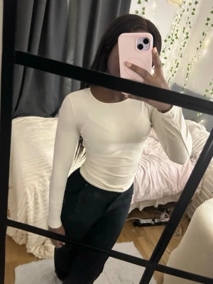 Vit långärmad ribbad topp - Säljer en stilren vit långärmad topp med rund hals. Toppen är ribbad och har en tight passform som framhäver figuren. Perfekt att matcha med jeans eller kjol för en enkel och snygg look. Krämvit!