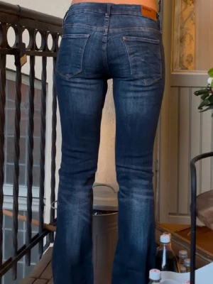 Levi's 517 blå bootcut jeans - Säljer ett par klassiska Levi's 517 jeans i mörkblå tvätt med bootcut-snitt. Jeansen har fem fickor, synliga sömmar och en läderpatch med Levi's-logga bak i midjan. Materialet är slitstarkt denim och passformen är normal med lite utsvängda ben.