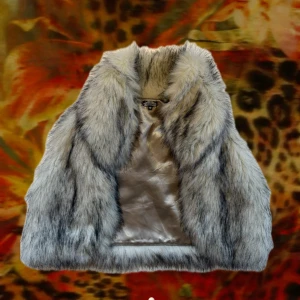 Lyxig pälsväst från bikbok - Säljer en fluffig och snygg pälsväst från bikbok i ljusgrå och beige ton med mörka inslag. Västen har en bred krage och är fodrad med glansigt tyg på insidan. Perfekt för dig som vill sticka ut med en cool och trendig look.