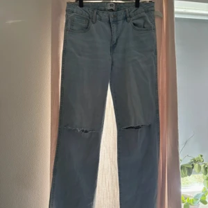 Ljusblå jeans med slitna knän från 157 - Ljusblå jeans från 157 med raka ben och slitna detaljer över båda knäna. Klassisk femficksmodell med knapp och dragkedja framtill samt fickor med lock bak. Jeansen har en avslappnad passform och är tillverkade i bomullsdenim.