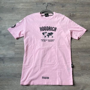 Rosa t-shirt från Hoodrich XS - Snygg rosa t-shirt från Hoodrich med svart tryck framtill och coola patches på ena ärmen. Modellen är rak med rund hals och korta ärmar. Skön bomullskvalitet och streetinspirerad design med texten 'From nothing to something'. Pris kan diskuteras