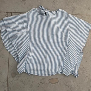 Topp, strl S - Säljer topp med blå och vita ränder. Toppen har vida, korta ärmar och knytning i nacken. Vet ej märket eftersom jag klippt av lappen. Är köpt i Spanien.