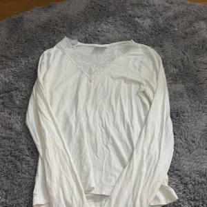 Vit långärmad blus med spets från Gina Tricot - Säljer en vit långärmad blus från Gina Tricot i storlek 158/164. Blusen har en v-ringad hals med fina spetsdetaljer som ger en romantisk touch. Perfekt för dig som gillar stilrena och feminina plagg. Materialet känns mjukt och lätt mot huden.