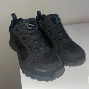 Svarta Treksta Bolt BOA sneakers - Svarta Treksta Bolt BOA sneakers med smart snörningssystem och robust design. Ovandelen är i slitstark syntet och mesh, med BOA-vridknapp för enkel justering. Skorna har platt sula och rund tå, perfekt för dig som gillar outdoor och äventyr. Använt dom en gång