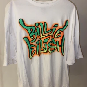 Billie Eilish t-shirt - Vit t-shirt med grönt/orange tryck från Bershkas kollektion med Billie Eilish från 2019. Använd en gång, skriv för fler bilder💕