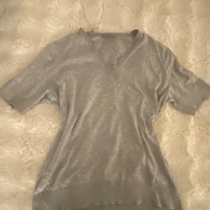 V-ringad grå tröja - Basic v-ringad grå T-shirt från COS i storlek XS men passar mera som S, i bra skick och ända defekten är minimal ( se bilder). ❤️