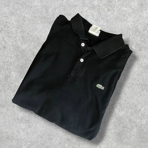 Lacoste Polo shirt  - Svart Polo-shirt från Lacoste. 🐊Autentisk och tillverkad i 100% bomull. Kontakta gärna för frågor. 🙌📲