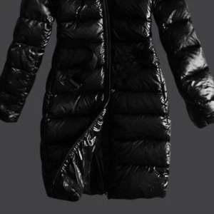 Svart lång pufferjacka med päls - Säljer en svart, glansig lång pufferjacka med fluffig brun päls runt huvan. Jackan har dragkedja framtill och är quiltad med breda kanaler. Perfekt för kalla dagar och har en riktigt snygg oversized look.  Dragkedjan de fram är lite trasig går ej att stänga men jackan har knappar att knäppa åt. 