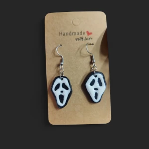 Scream örhängen - Unika handgjorda örhängen med Scream-mask motiv i svart och vitt. Hängande modell med krokar i metall och detaljerad ansiktsform, perfekta för dig som gillar skräck eller vill sticka ut med din stil. Halloween 