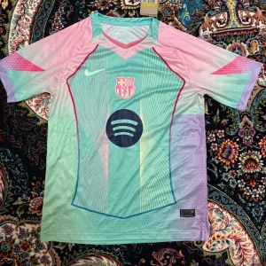 FC Barcelona x Nike fotbollströja pastell - Säljer en FC Barcelona fotbollströja från Nike i pastelliga färger med klubbmärke och Spotify-logga på bröstet. Tröjan har korta ärmar, V-ringning och coola grafiska linjer i mintgrönt, rosa och lila. Perfekt för dig som vill sticka ut på planen.