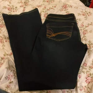 Mörkblå jeans från H&M Divided, strl 36 - Snygga mörkblå jeans från H&M Divided i storlek 36. Klassisk femficksmodell med kontrasterande orange sömmar och cool broderad detalj på bakfickan. Jeansen har normal passform och är tillverkade i slitstarkt denimtyg.Low/midwaist.