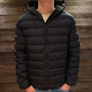 Mörkblå Colmar pufferjacka med huva - Säljer en mörkblå pufferjacka från Colmar med huva och dragkedja framtill. Jackan har två sidofickor med dragkedja och en quiltad design. Perfekt vinterjacka, riktigt varm. Storlek 50, vilket motsvarar small. Väldigt väldigt fint skick förutom en liten fläck på vänstersida. Fläcken syns däremot inte naturligt ljus som man kan se på första bilden, sista bilden är en närmare bild på fläcken, nypris 4500. Vid ytligare frågor kontakta mig mvh Melker  