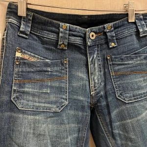 Diesel Larkee blå jeans straight fit - Snygga blå Diesel Larkee jeans med raka ben och klassisk femficksdesign. Jeansen har slitna detaljer, kontrastsömmar och logotyp på myntfickan. Säljer för att jag inte gillar hur de sitter på mig, skulle själv tipsa om att sy om till bootcut innerbenslängd:78cm
