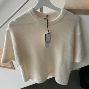 Vit stickad topp från Gina Tricot - Supermjuk och fluffig vit stickad topp från gina tricot med korta ärmar och rund hals. Perfekt för dig som gillar enkel och clean stil. 