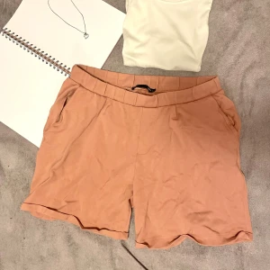 Rosa shorts i mjukt tyg - Mjuka och bekväma shorts i en varm rosa ton från märket Lager 157 (Est. 1999). Har elastisk midja med skön passform, fickor på sidorna och dekorativ bakficka. Tunna och följsamma i materialet – perfekta för sommar, semester eller chill hemma. Ger en avslappnad men snygg look som funkar till både linne, crop top och t-shirt. 🌺 Storlek: L 🌺 Färg: Dov rosa / dusty rose 🌺 Skick: Bra begagnat skick (lite nopprigt i tyget, se bild) 🌺 Material: Mjuk stretchig blandning 