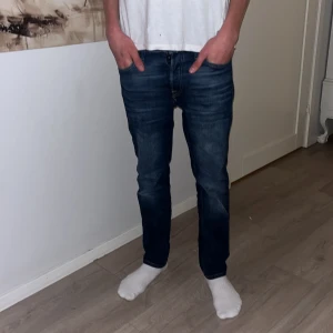 Blåa Jack & Jones jeans.  - Snygga mörkblå jeans från Jack & Jones med modellen Comfort Mike i storlek 29/30. Modellen har klassisk femficksdesign, raka ben och normal passform. Jeansen är tillverkade i slitstarkt denimtyg med snygga kontrastsömmar och subtila tvättade detaljer för en cool look. Modellen är 182.
