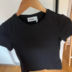 Svart kortärmad topp från Weekday - Kortärmad topp från weekday i polyester material och formar sig efter kroppen. 