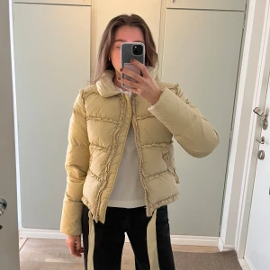 Beige pufferjacka från Blumarine  - Ljus beige dunjacka från Blumarine. Jackan är vintage så finns små märken på den. Så fin!! Italiensk storlek 42 vilket är small. Den är väldigt lång i ärmarna vilket är skönt när det är kallt 