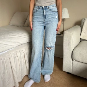 Ljusa wide jeans från H&M - Säljer dessa superfina högmidjade jeans i ljusblå tvätt. Raka ben och lite vidare passform – sitter jättesnyggt i midjan och är riktigt bekväma! Har en liten slitning på ena knät. Jag är 168 cm