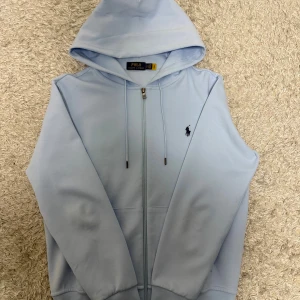 Ralph Lauren Zip Hoodie - Säljer nu min Ralph Lauren zip hoodie som är använd 1-2 ggr, inprincip nyskick. Storlek S. Färgen babyblue som är as snygg och unik. Har du fler funderingar kontakta mig.