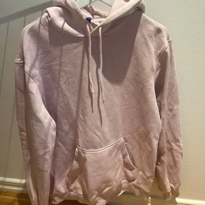 Ljusrosa hoodie med huva och ficka - En basic oversized ljusrosa hoodie med huva och dragsko, samt en stor magficka framtill. Tröjan har långa ärmar och är gjord i mjuk bomullsmix, perfekt för chill dagar eller när du vill vara extra comfy.