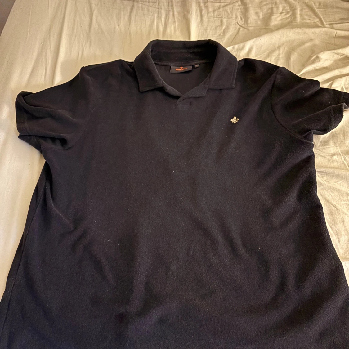 Svart piké med broderad detalj