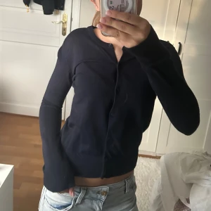 Mörkblå kofta med knappar - En stilren mörkblå kofta med rund hals och knäppning framtill. Långärmad och i mjukt, tunt material som passar perfekt till lager-på-lager. Enkel och clean look som funkar till allt, och sitter snyggt med en lite croppad passform.