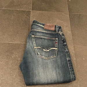 Replay jeans  - Snygga blå Replay jeans i straight fit med slitningar och coola detaljer på bakfickan. Storlek W 32 L34