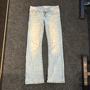 Ljusblå jeans från Gina Tricot, 164 - Säljer ett par ljusblå jeans från Gina Tricot i storlek 164. Jeansen har klassisk femficksdesign, låg midjad bootcut. Snygga detaljer på bakfickorna med knappar. 