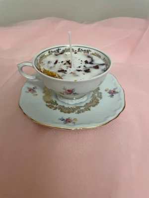 Doftljus i en vit tekopp med blommor i doft utav vanilj nr 2  - Det här ljuset är gjort av återanvändbara material. Tekoppen är köpt secondhand och stearinet är från kyrkor som tänkte slänga det. Det här ljuset har en svag doft utav vanilj, så känsliga även kan använda det. Det här ljuset har även torkade blommor och torkad apelsin på som dekoration. Det finns fler av denna design på hemsidan om man vill köpa sets. 