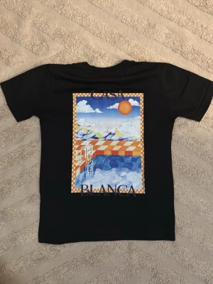 Casablanca t-shirt - Säljer en svart t-shirt från Casablanca med färgglad poolgrafik på bröstet och ryggen. Trycket har sol, moln och schackrutigt mönster i orange och vitt. Klassisk rund hals och korta ärmar. Kan gå ner i pris vid snabb affär, kom privat!