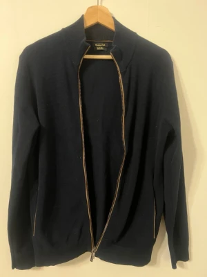 Marinblå kofta med dragkedja Massimo Dutti - Snygg marinblå kofta från Massimo Dutti i mjuk stickad bomull. Klassisk modell med hel dragkedja framtill och ribbade muddar. Perfekt till lager på lager och funkar året runt. Enkel och stilren design som passar till det mesta.