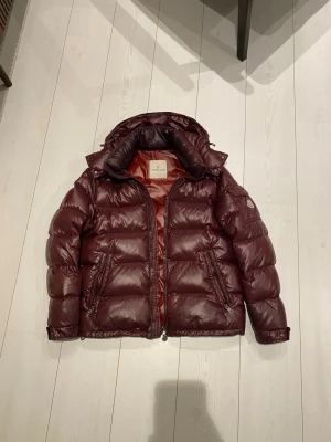 Moncler maya jacka - Tjenare säljer en vinröd pufferjacka från moncler! Köptes på garmsmarket för 2 år sedan! Svin snygg färg som verkligen sticker ut i alla väder. Ett litet hål på högra armen (på baksidan) så syns knappt!  Mvh Måns 