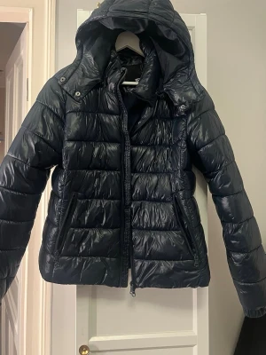 Mörkblå pufferjacka med luva  - Säljer en mörkblå pufferjacka från lager 157 med glansig yta och huva.  Säljs inte i butik längre! 